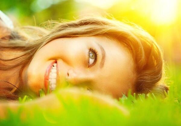 Beautiful teenage Girl lying on field of green grass close-up ov